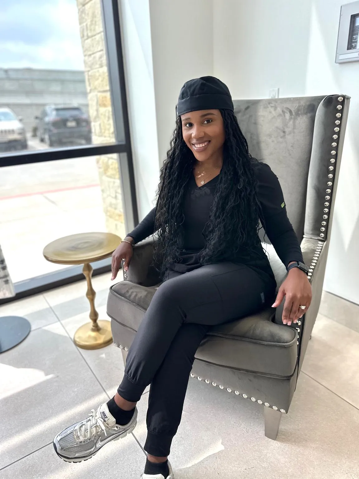 Ashley Newman, Registered Nurse and wellness coach, seated in black scrubs