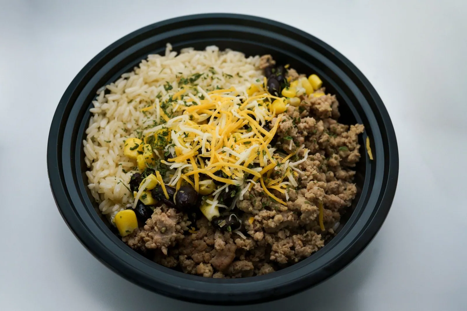 A freshly prepared taco-style bowl with rice, seasoned turkey, corn and beans
